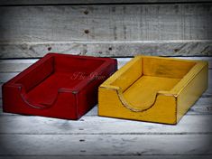 two small wooden boxes sitting on top of a wooden floor next to each other, one red and one yellow