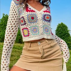 a woman wearing a white crochet top and tan skirt is posing for the camera