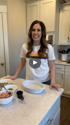 a woman standing in front of a kitchen counter with bowls and food items on it