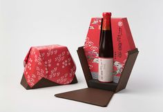 a bottle of wine sitting inside of a red box next to a brown paper bag