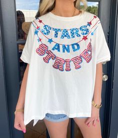 Embrace the patriotic spirit with our Stars and Stripes Top! Featuring sequined stars and stripes garland embroidery, this short sleeve top will add a touch of glamour to any outfit. The asymmetric high-low cut and round neck provide a comfortable and stylish fit. Perfect for showing off your American pride! Maddy is wearing a size Small. Height is 5’7, Bust is 34”, Waist 27”, and Hips 33”. Summer Short Sleeve T-shirt With Sequins, Patriotic Star Print Short Sleeve Tops, Patriotic Star Print Short Sleeve T-shirt, Patriotic Short Sleeve Top With Star Print, Patriotic Short Sleeve T-shirt With Star Print, Summer T-shirt With Sequins And Short Sleeves, Summer Cotton T-shirt With Sequins, Summer Sequined Short Sleeve T-shirt, Spring Americana T-shirt With American Flag Print