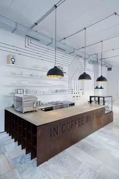 the inside of a coffee shop with lots of counter space and hanging lights above it