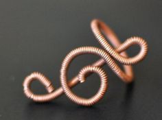 a ring made out of copper wire on a black surface with the letter s in the middle