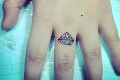 a person's hand with a small tattoo on the middle finger and an outline of a diamond