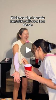 two girls are laughing while one girl holds a red cup and the other is holding a pink cup