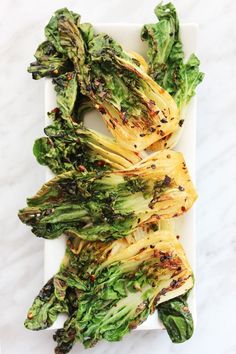 grilled broccoli on a white plate with black pepper sprinkles