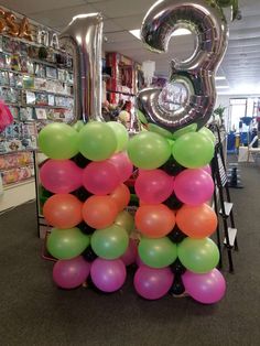 balloons are stacked up in the shape of the number twenty five on display at an office