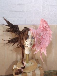 a mannequin's head with pink feathers on top of a wooden stand