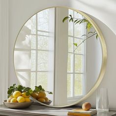 a round mirror sitting on top of a table next to a bowl of lemons