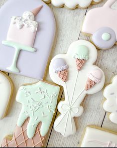 some decorated cookies are laying on a white wooden table and one is pink, the other is blue