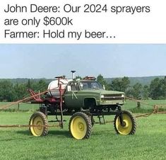 a green tractor with two large wheels parked in a field