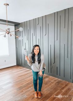 a woman is standing in an empty room with her hand up to the ceiling and holding a light bulb