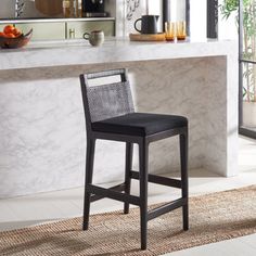 a black counter top sitting next to a bar with a white counter and chair in front of it