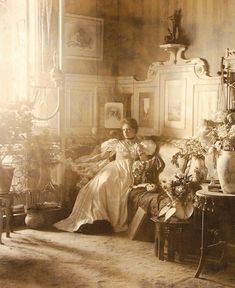 an old black and white photo of a woman sitting in a room