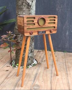 an old fashioned radio sitting on top of a wooden stand next to a small tree