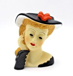 a ceramic figurine of a woman wearing a black hat with a red bow