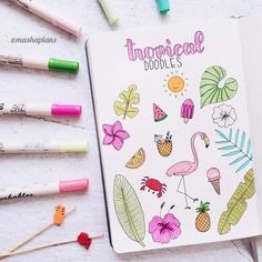 an open notebook with tropical doodles on it next to crayons and markers