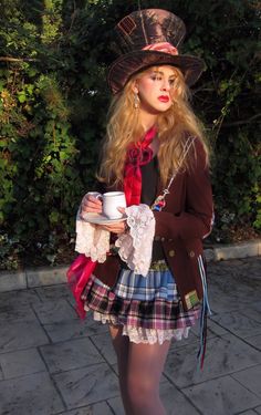 a woman in a skirt and top hat holding a cup