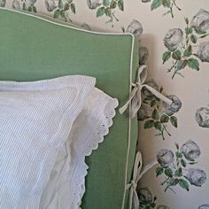 a green bed with white ruffled pillows and floral wallpaper