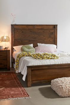 a bed with white sheets and pillows on top of it next to a brown rug