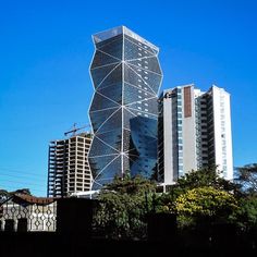 a very tall building sitting in the middle of a city next to some trees and bushes