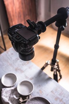 a tripod is set up on a table with three bowls and two cups in front of it