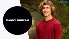 a young man in a red shirt standing next to a black circle with the words danny duncan on it