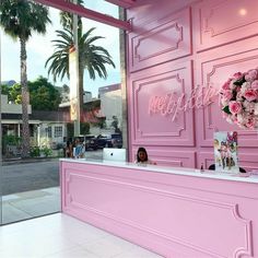 a pink reception counter with flowers on it in front of a window that says hollywood