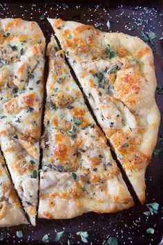 four slices of pizza sitting on top of a metal pan covered in cheese and herbs