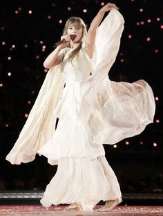 taylor swift performing on stage in white dress