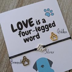 a bracelet with two dogs and paw prints on it that says love is a four legged word