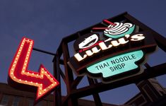 a neon sign that says lulla's thai noodle shop with an arrow pointing up