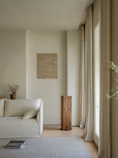 a living room with a white couch and some curtains on the window sill in front of it