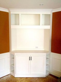 an empty room with some white shelves and cupboards on the wall in front of it