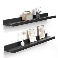 two black floating shelves with pictures and vases on each shelf, one is empty