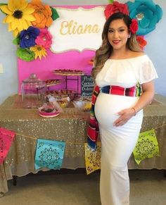 a pregnant woman standing in front of a table with flowers on it and a sign that says etna