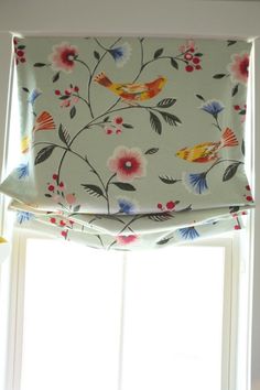 a window with a flowered valance hanging from it's side next to a window sill