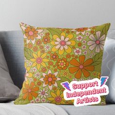 a pillow with the words support independent artists in pink and orange flowers on green background