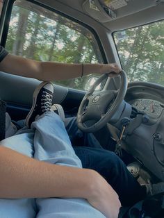 a person sitting in the driver's seat of a truck with their feet on the steering wheel