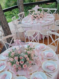 the table is set with pink and white plates, napkins, and flowers in vases