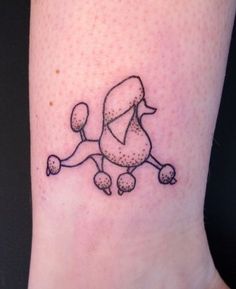 a small black and white poodle tattoo on the ankle, with dots all over it