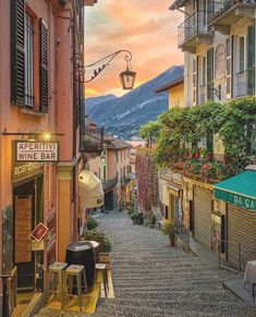 an alley way with tables and chairs in the foreground, mountains in the background