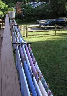 a long wooden fence with many different colored surfboards on it's posts and some cars parked in the background