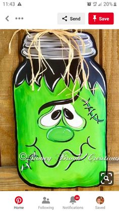 a green mason jar with a face painted on it and tied to a wooden fence