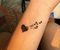 a woman's wrist tattoo with musical notes and hearts on her left arm,