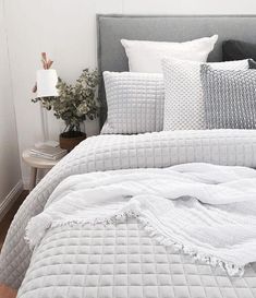 a bed with white sheets and pillows on top of it in a bedroom next to a nightstand