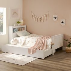 a small child's bedroom with pink walls and white furniture, including a bed