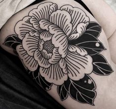 a black and white flower tattoo on the back of a woman's thigh,