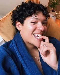 a person laying on a bed with a towel around their neck and smiling at the camera