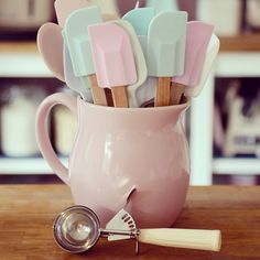 a pink mug filled with marshmallows sitting on top of a wooden table